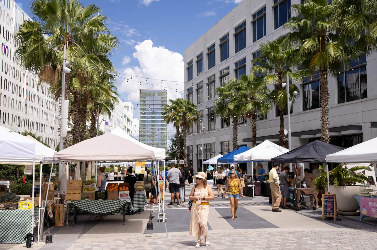 Shoppers browsing vendor tents at Lake Nona Farmers Market at Laureate Park