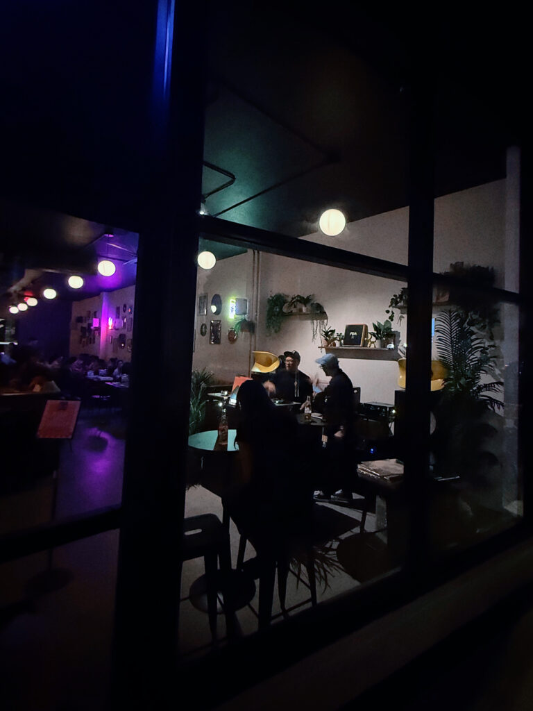 Players with bingo cards and pizza at tables inside Perla's Pizza