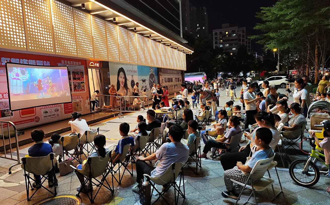 Moviegoers on blankets at an outdoor lawn screening